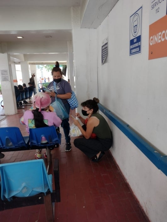 Woman kneeling down in a hallway speaking to a patient.