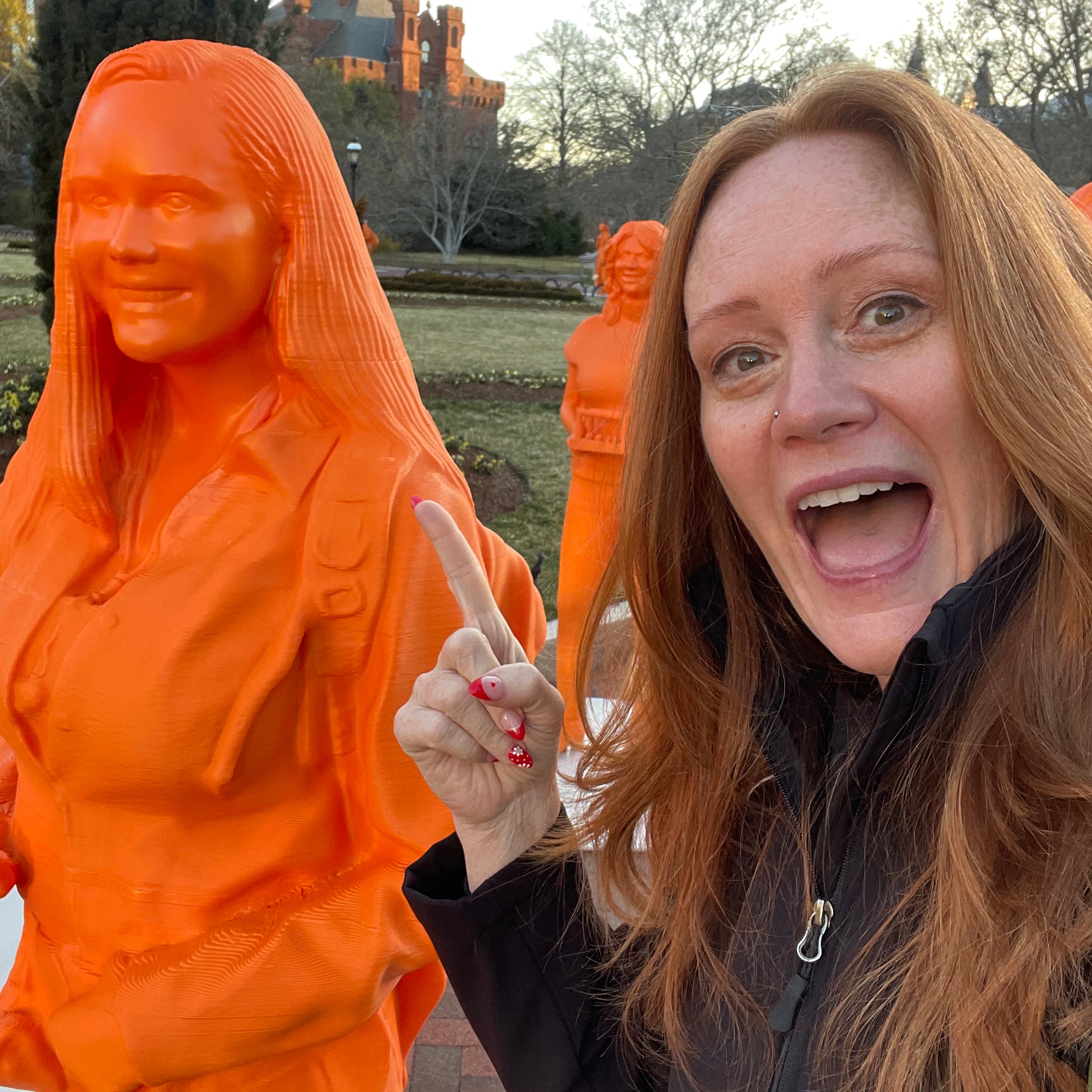 woman pointing at orange statue of herself