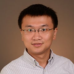 Portrait of man with short dark hair and glasses wearing button up shirt