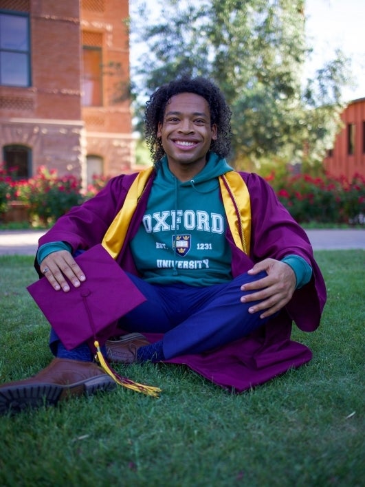 ASU grad William Walker VI smiling while seated on Old Main lawn at the Tempe campus.