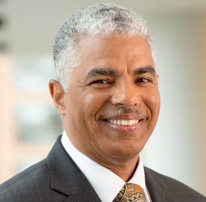 Man in white hair and suit smiling